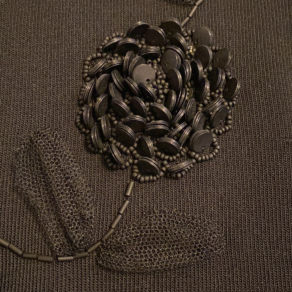 Intricate flower and leaf designed front sleeveless mock turtleneck.